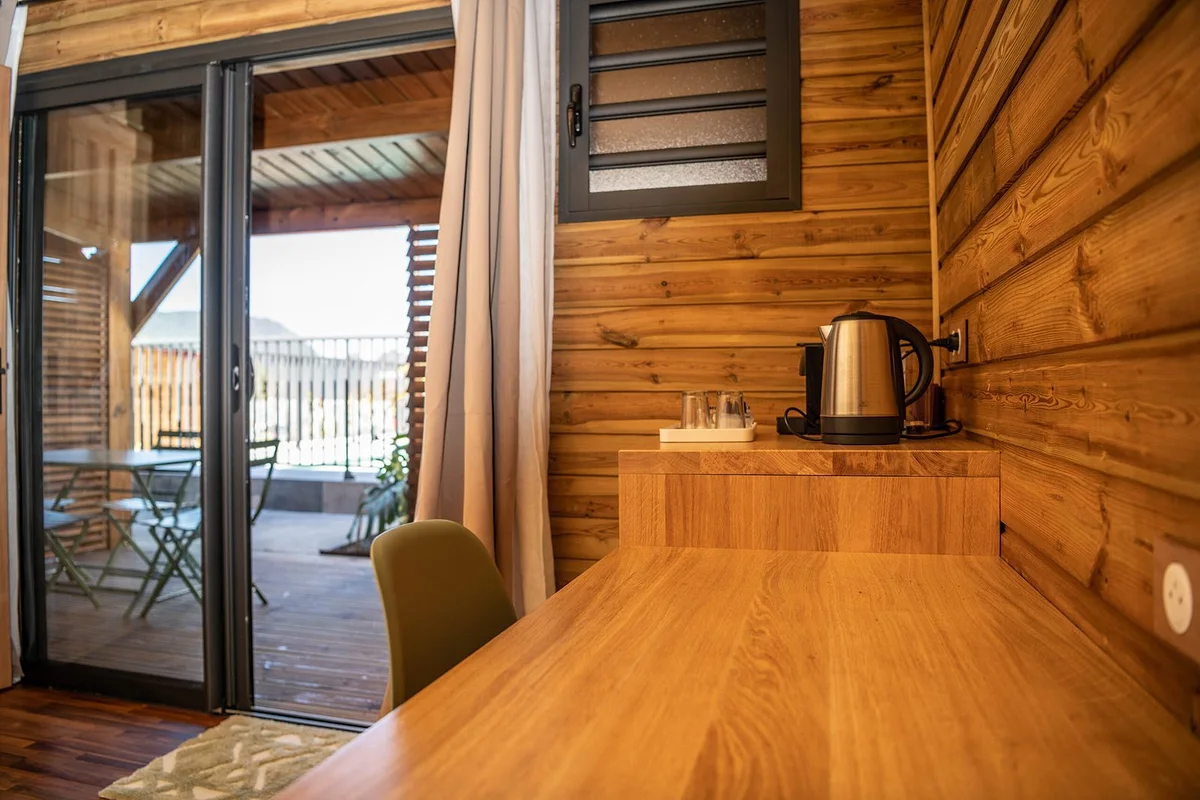 Le bureau en bois, la bouilloire et la baie ouverte sur la terrasse