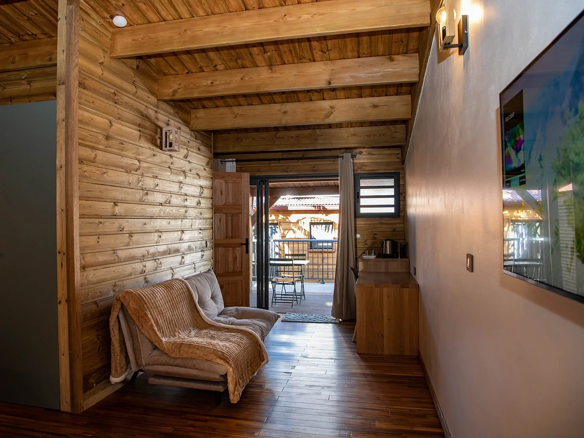 Le coin salon d'un lodge, son fauteuil et la baie ouverte sur la terrasse