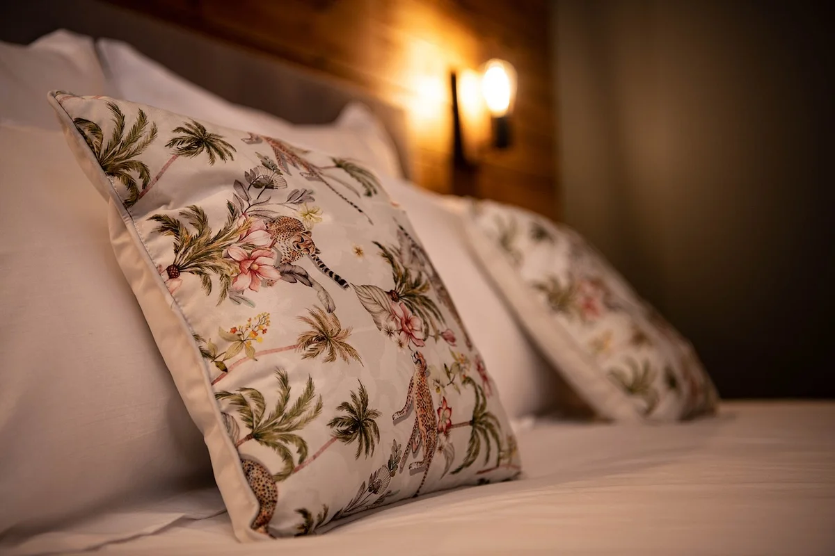 Un coussin aux motifs de feuillage posé sur le lit
