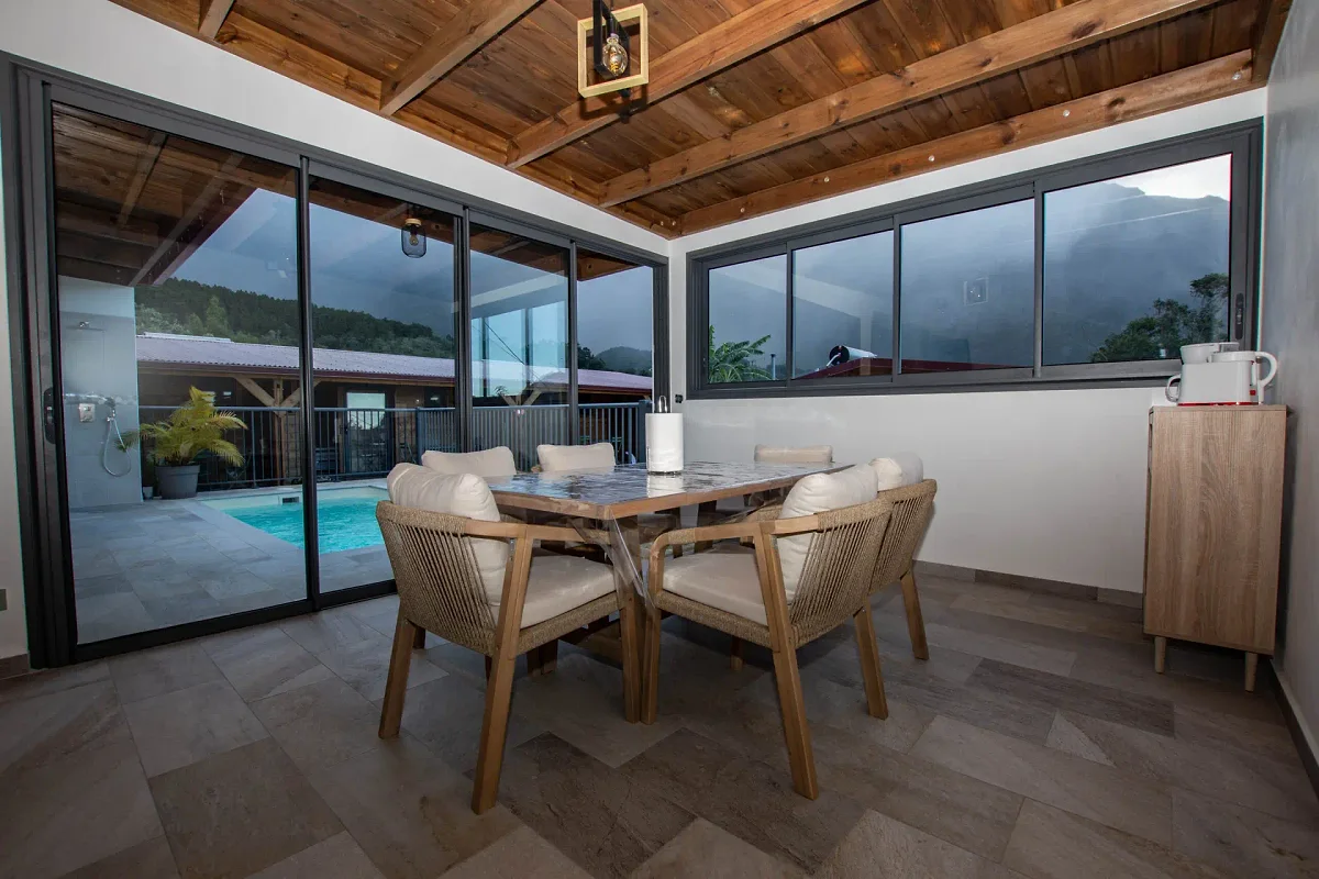 La cuisine commune équipée, sa table pour six et la vue sur la piscine