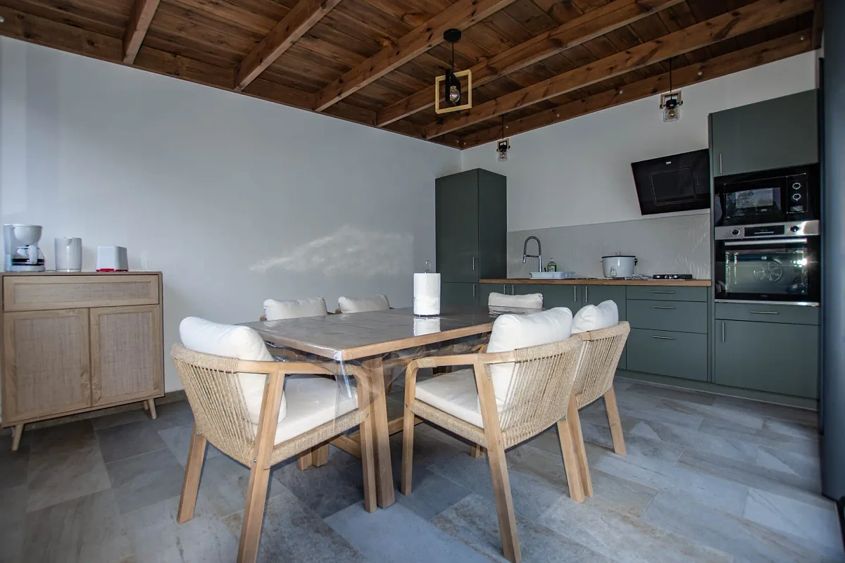 La cuisine commune, ses meubles gris, le four et la table pour six
