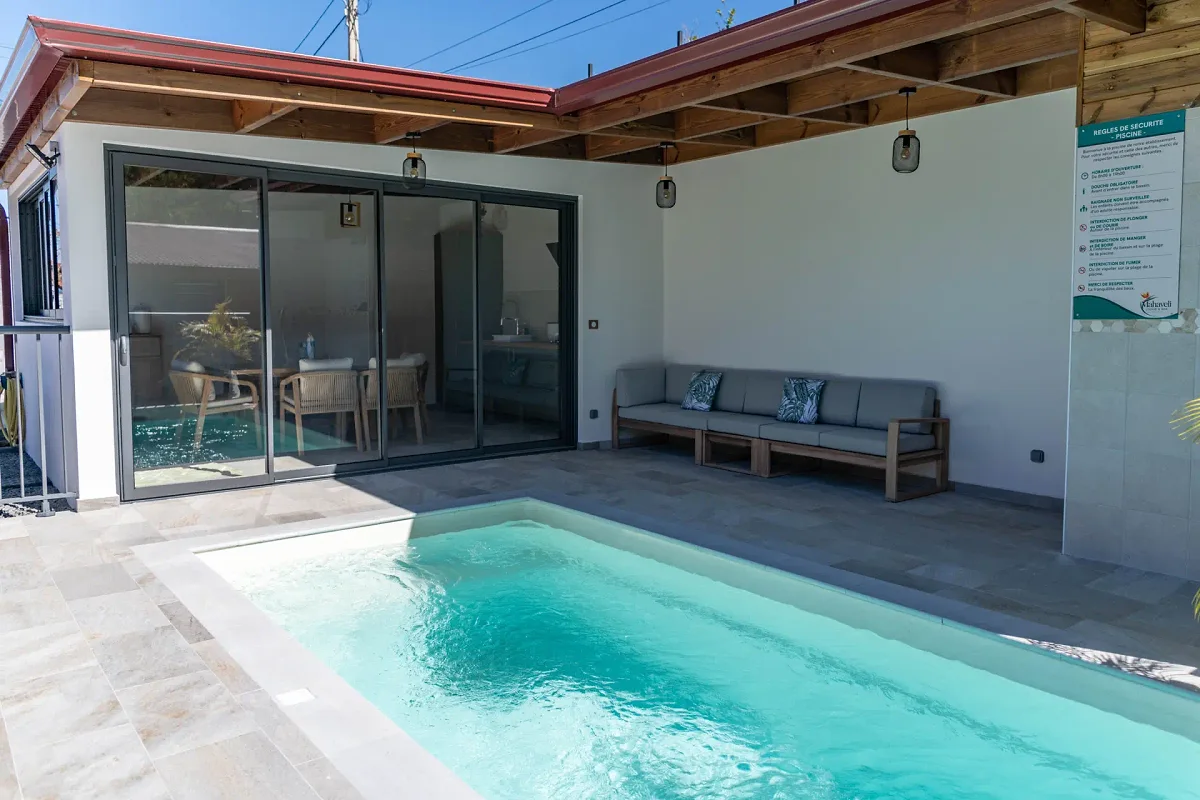 La piscine chauffée bordée de dalles claires et son salon de jardin