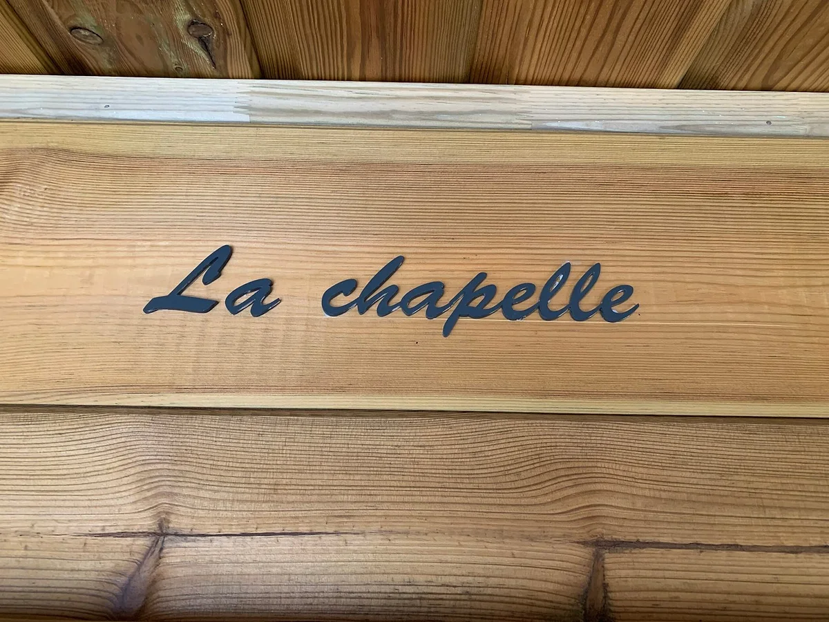 La plaque de bois gravée « La chapelle » à l'entrée du lodge
