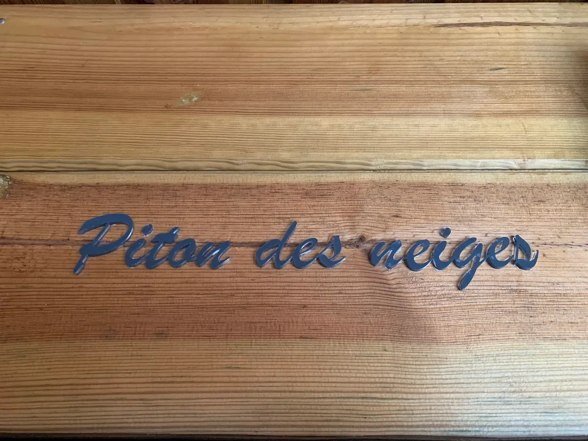 La plaque de bois gravée « Piton des neiges » à l'entrée du lodge
