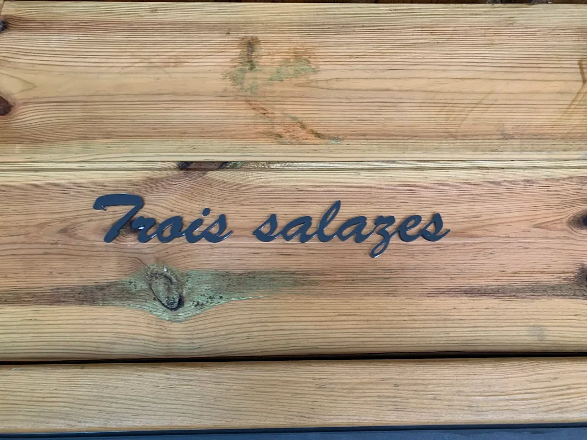 La plaque de bois gravée « Trois salazes » à l'entrée du lodge