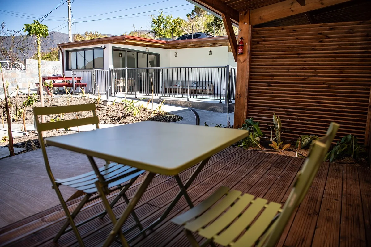 La terrasse en bois d'un lodge, sa table et ses chaises vertes